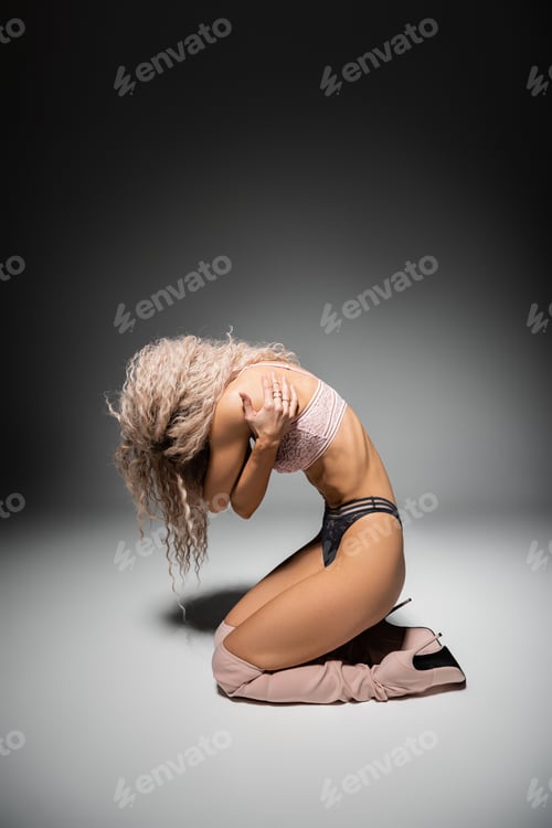 Preview: full length of seductive and sexy woman in lace lingerie and high boots hugging herself on black