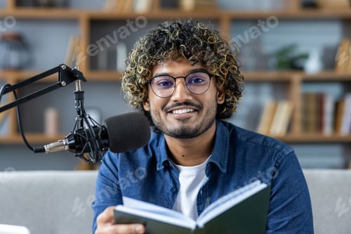 Preview: Confident young man podcasting with microphone and holding a book