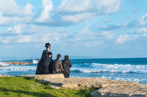 Preview: Religious Jew family sitting on the coast of Mediterranean sea in Israel and watching the waves.