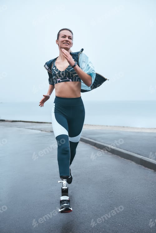 Preview: Can't live without sport. Vertical photo of strong disabled woman in sportswear is running