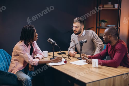 Preview: Three radio hosts interviewing a guest in a professional podcast studio, engaging in a discussion