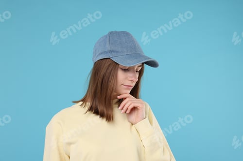 Preview: Young woman wearing stylish denim baseball hat on light blue background