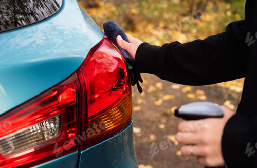 Preview: Closeup picture, image young woman, driver, dry wiping her car with microfiber cloth after washing