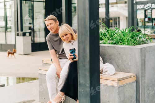 Preview: Affectionate Couple Sitting Outdoors on Modern Concrete Bench