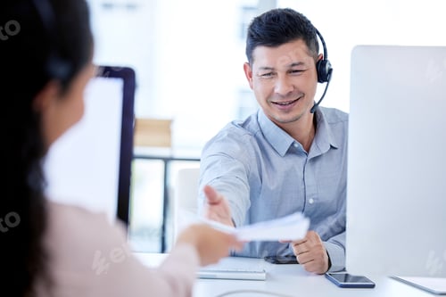 Preview: Shot of a young call centre agent sitting and working with a colleague in the office