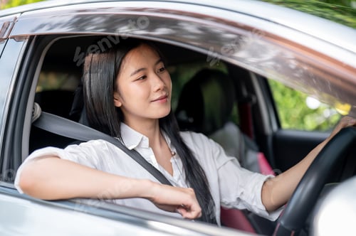 Preview: Asian woman in white shirt looking ahead from inside a car parked at the parking lot or roadside.