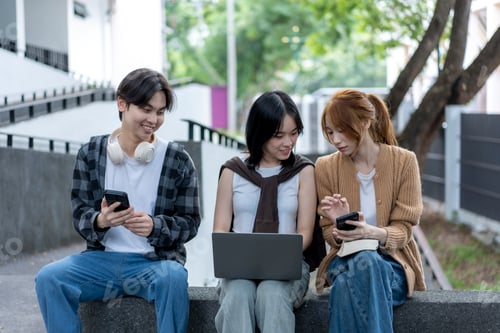 Preview: Three young people are sitting on a bench, looking at their cell phones