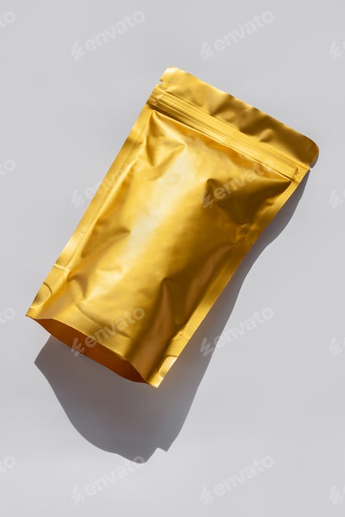 Preview: Golden metalized pouch bag with coffee beans top view with shadow isolated on white background. Food