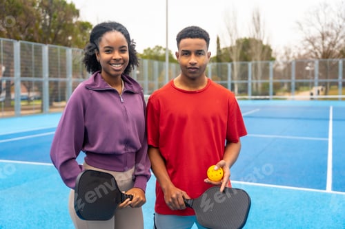 Preview: Young couple enjoying sport with pickleball rackets