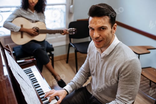 Preview: Man playing piano near woman playing guitar in studio