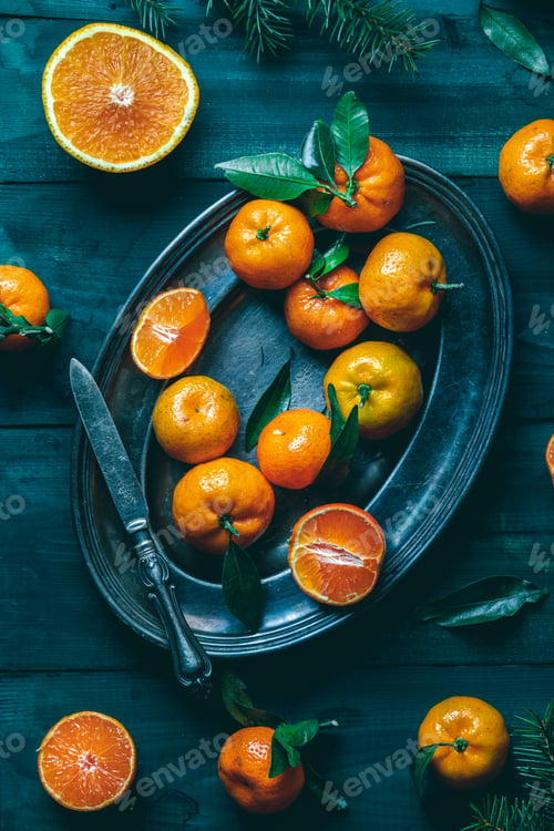 Preview: Tangerines with green leaves on a green wooden table in a rustic style surrounded by spruce branches