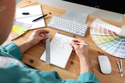 Preview: Man drawing in sketchbook with pencil and ruler at wooden table, closeup