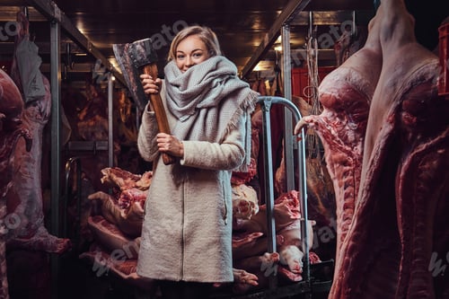 Preview: Blond female in a warm jacket in a meat freezer storage.