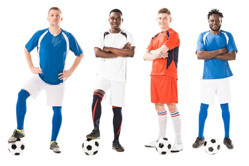 Preview: confident young multiethnic soccer players standing with balls and looking at camera isolated on