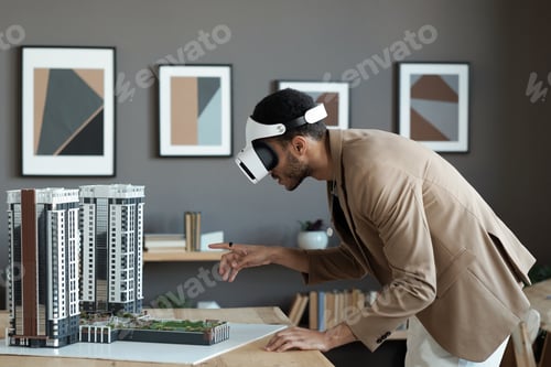 Preview: Young biracial businessman bending over table and pointing at house layout