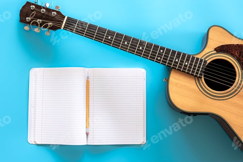 Preview: Acoustic guitar and notepad on a blue background, top view.