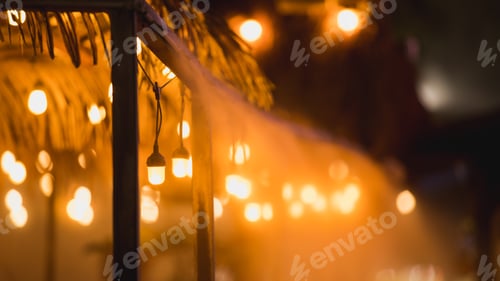 Preview: Ambient bokeh lights from lightbulbs on the building exterior of an outdoor restaurant at night.