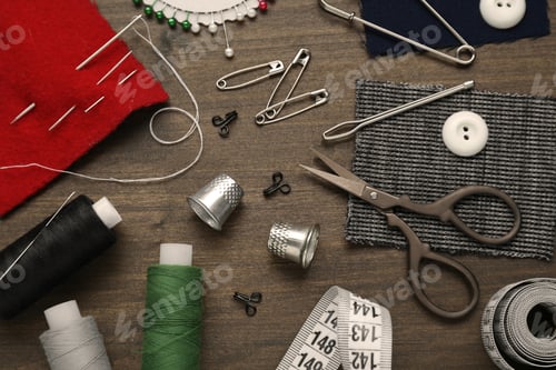 Preview: Flat lay composition with thimbles and different sewing tools on wooden table