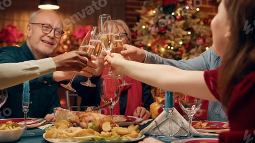 Preview: Happy family members toasting champagne while sitting at Christmas dinner table at home