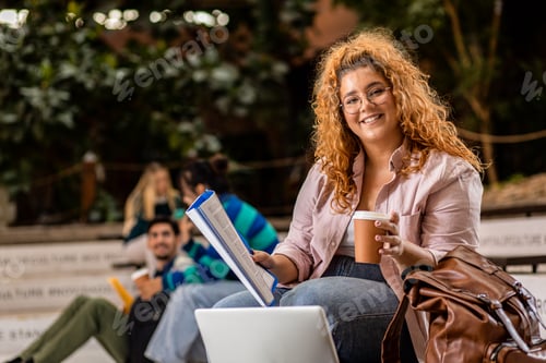 Preview: Portrait of female student siting in campus using laptop.