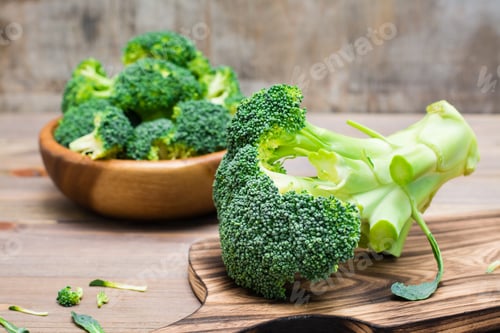Preview: fresh uncooked broccoli on a cutting board and divided into inflorescences in a wooden plate