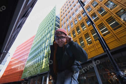 Preview: Young man adjusting glasses in vibrant london city