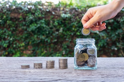 Preview: Hand Putting Coin in Jar Saving Money Concept