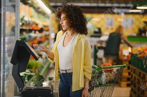 Preview: Customer weighing broccoli on digital scale in supermarket