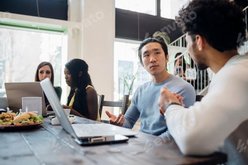 Preview: Young businessmen having discussion at cafe table