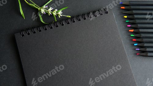 Preview: A black notebook and colored pencils are on the table. Workplace.