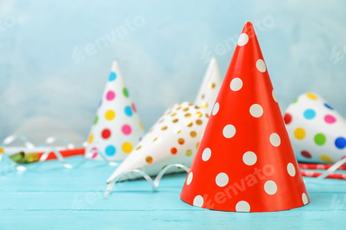 Preview: Birthday party caps on table against color background