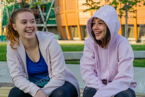 Preview: Caucasian women sitting on stone talking and happily smiling - the concept of friendship