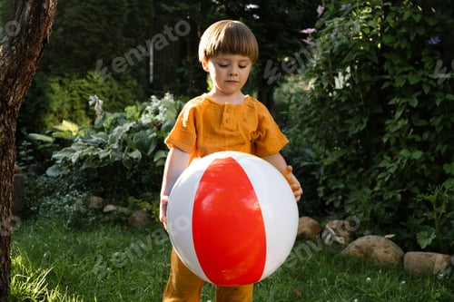 Vista previa: Small boy playing with beach ball on lawn in summer.