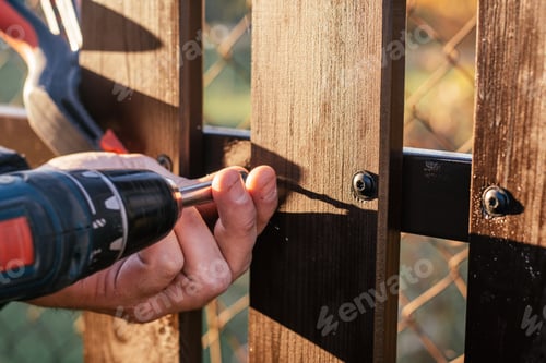 Preview: Hand of carpenter holding stud driving machine putting screw into wooden plank