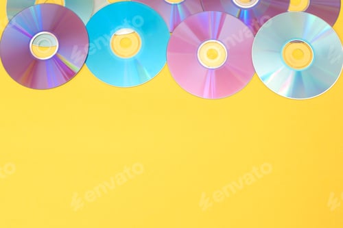 Preview: Many colourful compact discs on a vibrant yellow background with copy space