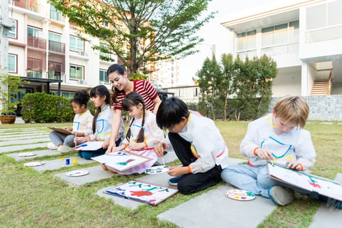 Preview: Group of student coloring on painting board outdoors in school garden.