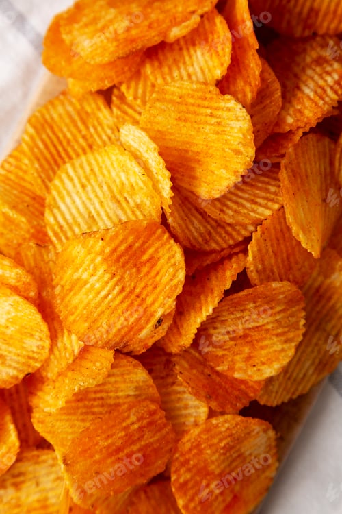 Preview: Paprika Flavored Crinkle Potato Chips on a Wooden Board, top view. Close-up.