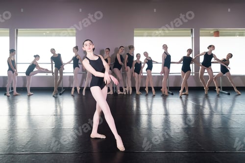 Preview: Teenage girl in ballet dance studio poses with the rest of the class behind her