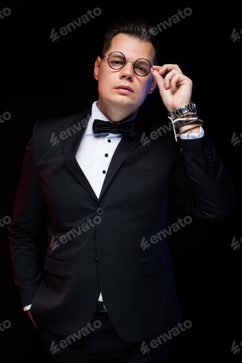 Preview: Portrait of confident handsome elegant stylish businessman with bow-tie holding glasses with his
