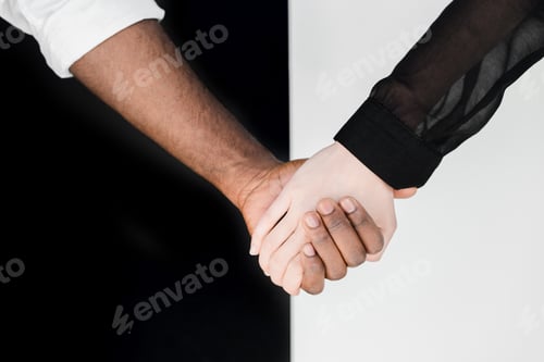 Preview: cropped image of multicultural couple holding hands, yin yang concept