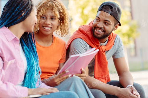 Preview: Group of smiling stylish African American student with books and backpacks, talking