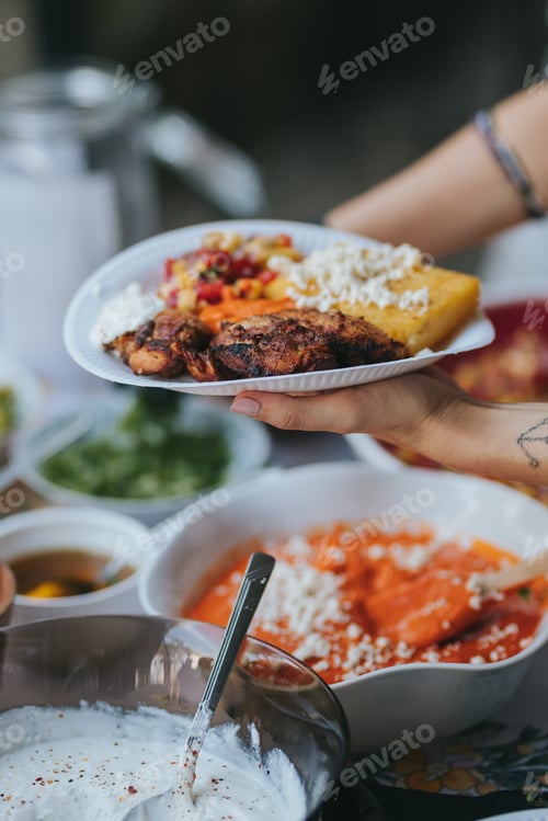 Preview: Chef holding in hand a plate with Mexican chicken, fried Polenta, cheese, vegetables and sour cream