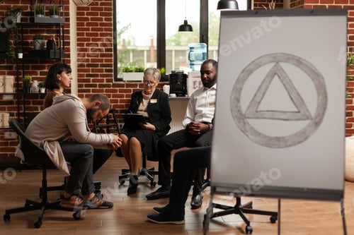 Preview: People sitting in circle at group therapy session while having aa meeting sign in office