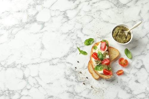 Preview: Toasted bread with tasty cream cheese and tomatoes on marble table, flat lay. Space for text