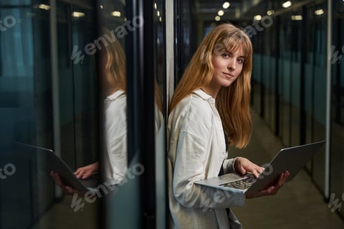 Preview: Woman designer standing with laptop in office corridor