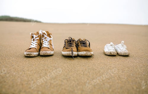 Preview: Three pairs of shoes with different sizes on the beach