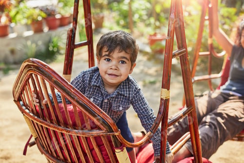 Preview: Little boy enjoying a sunny day on a wicker swing