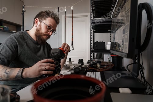 Preview: Photographer cleaning camera lens in a well-equipped studio