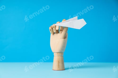 Preview: Wooden hand with paper plane on blue background