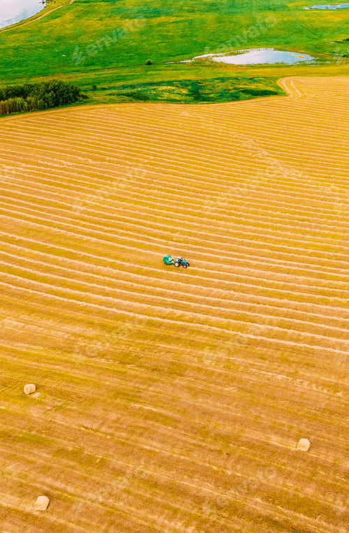 Preview: Aerial View Tractor Collects Dry Grass In Straw Bales In Wheat Field. Special Agricultural Equipment